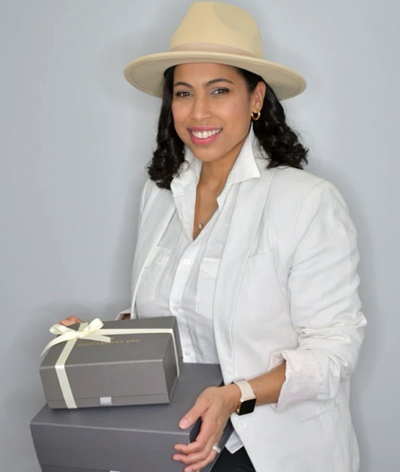 Sarah, co-founder of Occasions Box, holding two Occasions Box gift boxes, the top one finished with an ivory ribbon